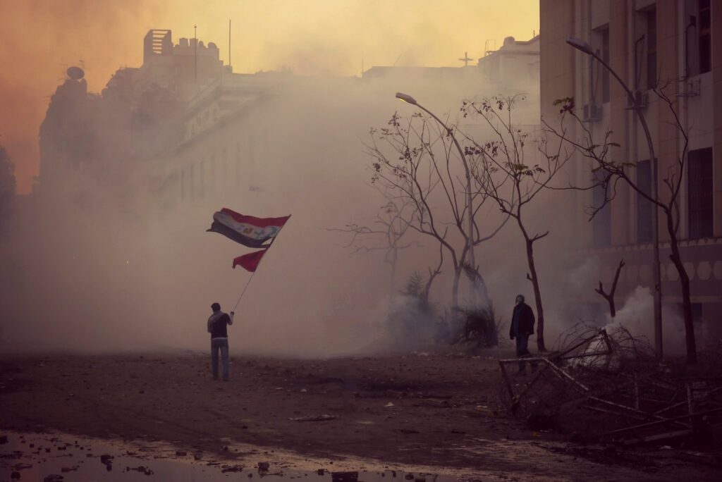 معترض مصری پرچمی با دو نشان اسلام و مسیحیت را به نشانه اتحاد بالا برده است. قاهره، انقلاب ۲۰۱۱ (Fickr /Alisdare Hickson)
